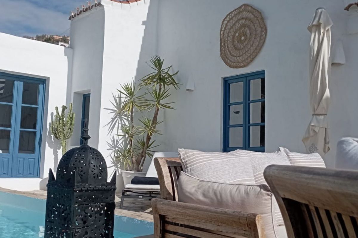 Patio encalado con sofá y puerta azul en una de las viviendas